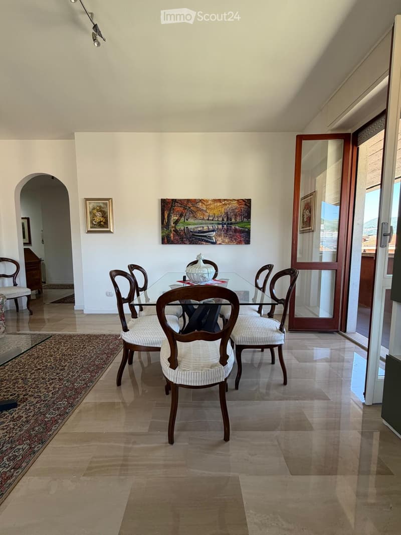 Dining room with a glass dining table, six chairs, a sideboard, and artwork on the walls.