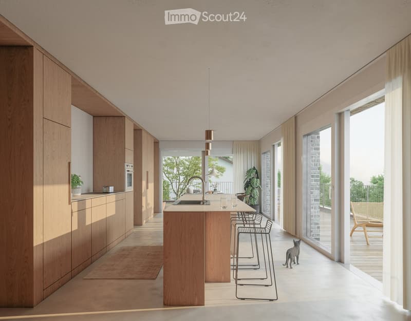 Modern kitchen with light wooden cabinets, a central island, and a sink. There are stools, a chair, and a cat visible. Large windows and sliding doors lead to a balcony.