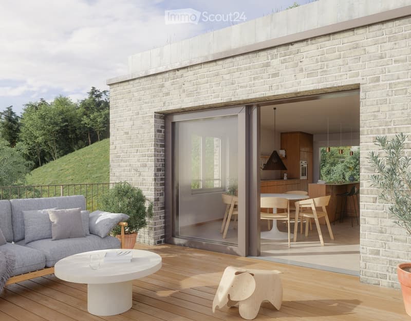 Modern balcony with wooden decking, grey sofa, white coffee table, small wooden stool, and potted plants. Open sliding doors lead to a dining area with a round table and chairs.