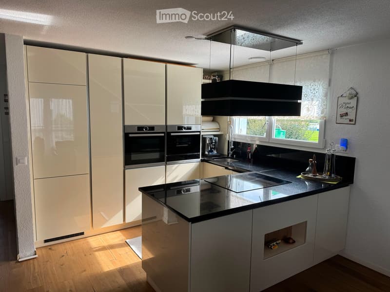 Modern kitchen with white cabinets, black countertops, stainless steel appliances, and a central island with an induction stove.