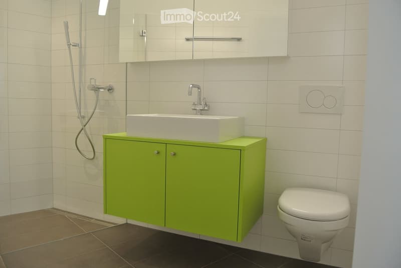 modern bathroom with white tiles, green cabinet, white sink, white toilet, shower