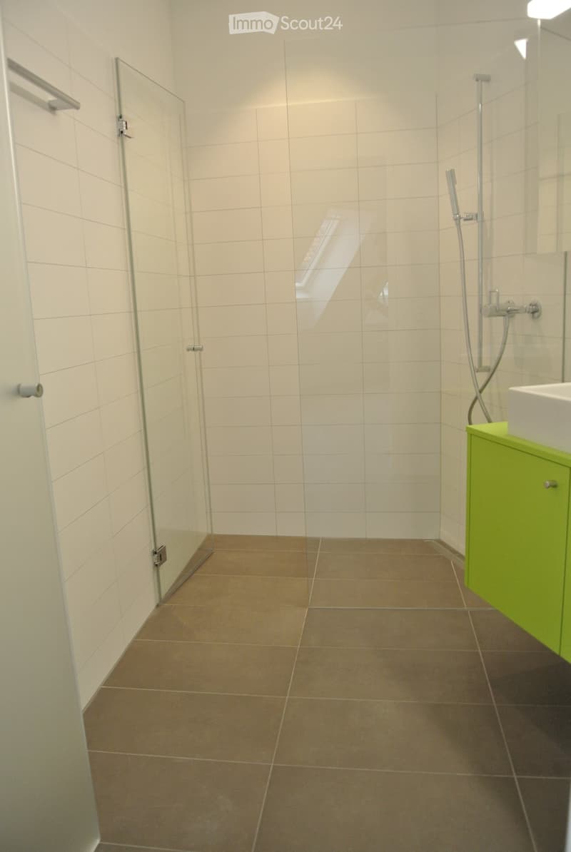 white walls, tiled floor, glass shower door, shower fixture, green cabinet, white sink