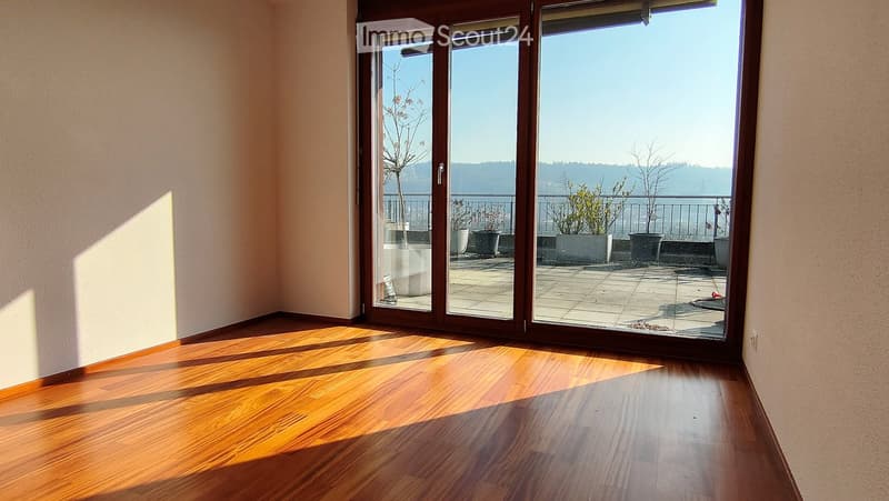 Spacious balcony with wooden flooring, large glass sliding doors, and a scenic view of the landscape beyond.