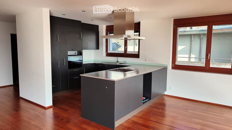 Modern kitchen with dark cabinets, stainless steel appliances, and a central island with a countertop.