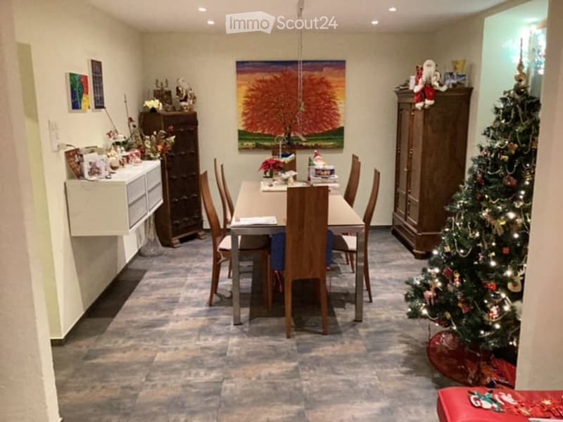 Dining room with a dining table and chairs, a cabinet, a Christmas tree, and decorative items on shelves.