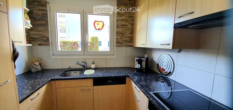 Modern kitchen with granite countertops, wooden cabinets, stainless steel sink, coffee maker, and decorative items.