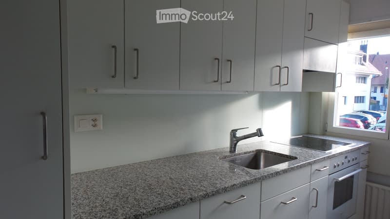 Modern kitchen with white cabinets, granite countertop, stainless steel sink and faucet, and built-in oven.