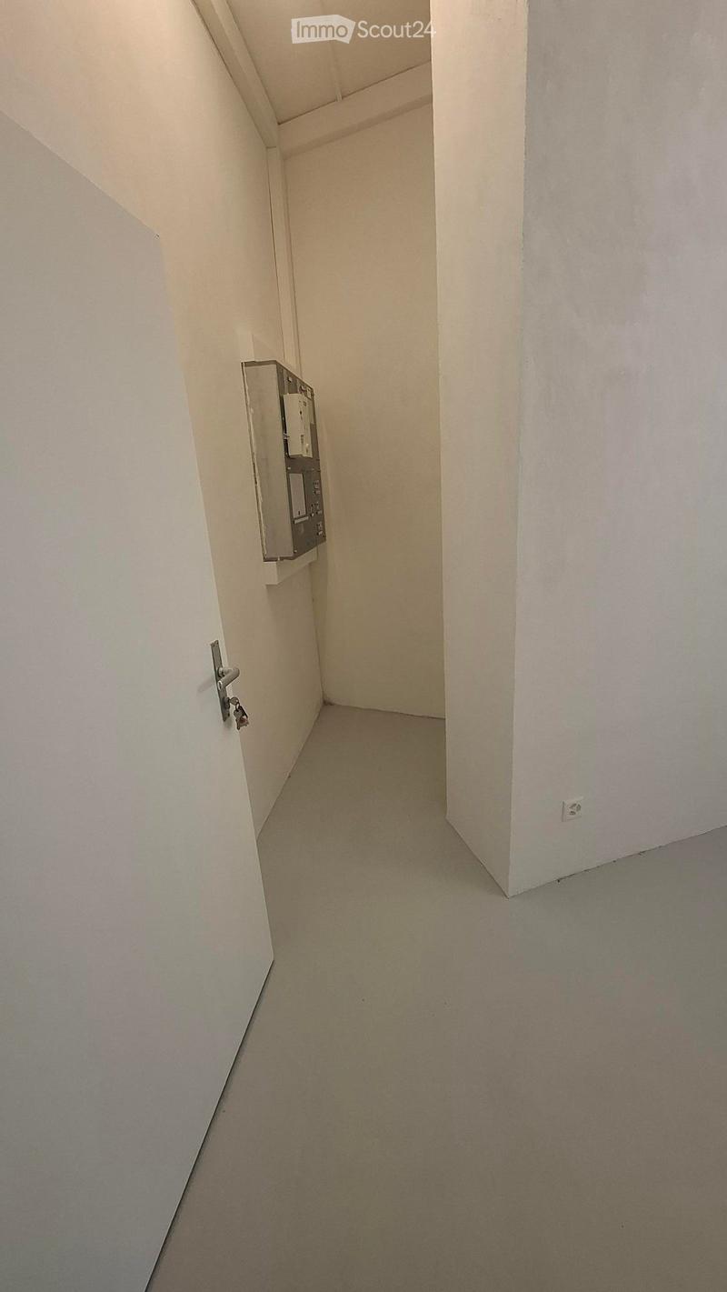 Empty hallway with white walls, light-colored carpet, and a door on the left side.