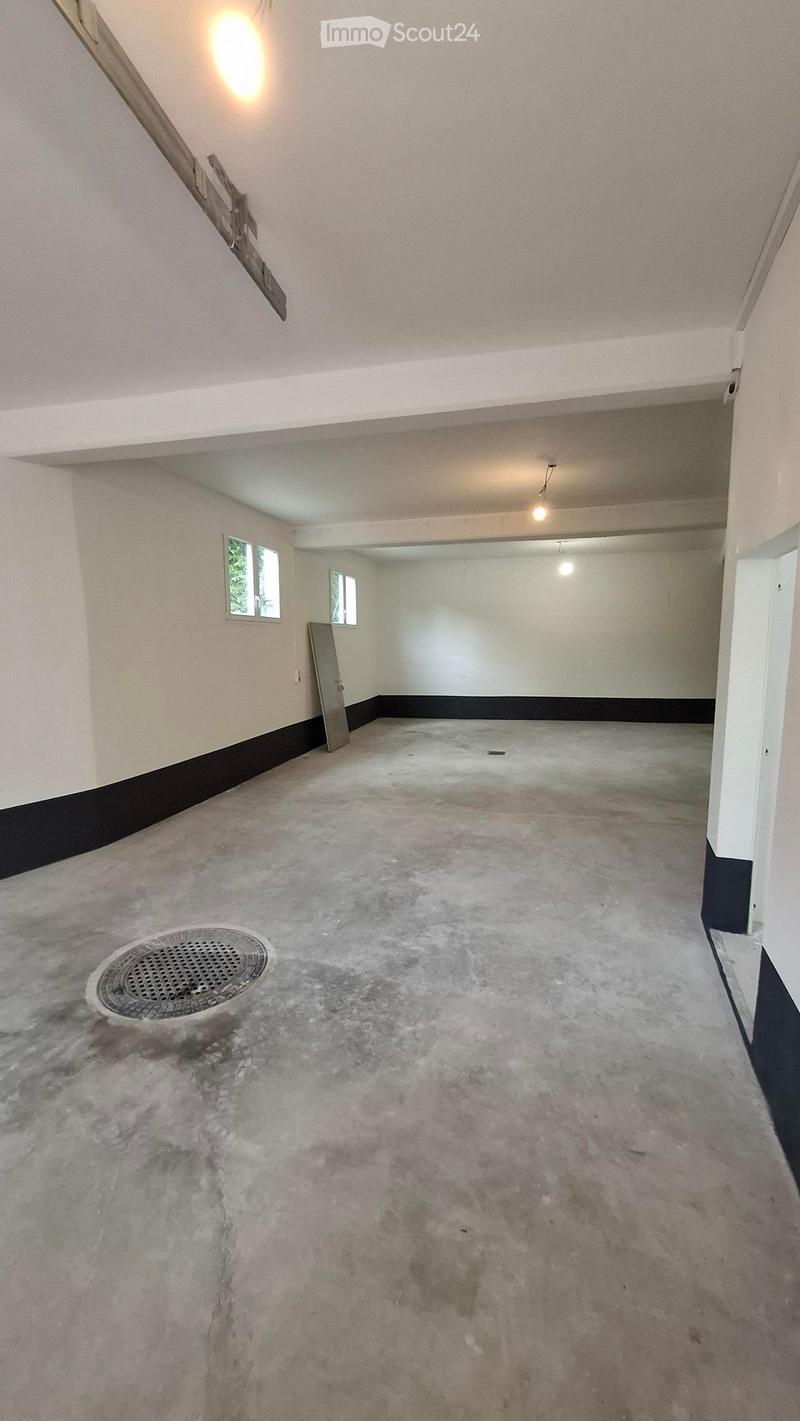 Empty room with concrete floor, white walls, small windows, and a metal door. No furniture or equipment present.