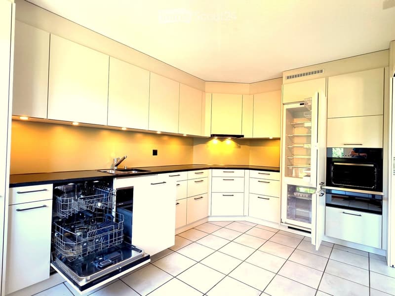 Modern kitchen with white cabinets, stainless steel appliances, and a black countertop.