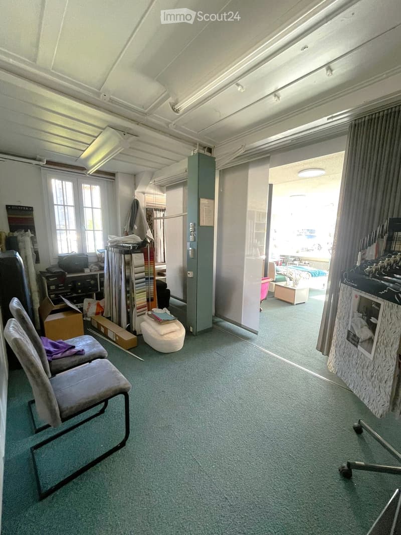 empty room, carpeted floor, white ceiling, two chairs, storage boxes, white ottoman, open door, window, shelves, bed, table, lamp