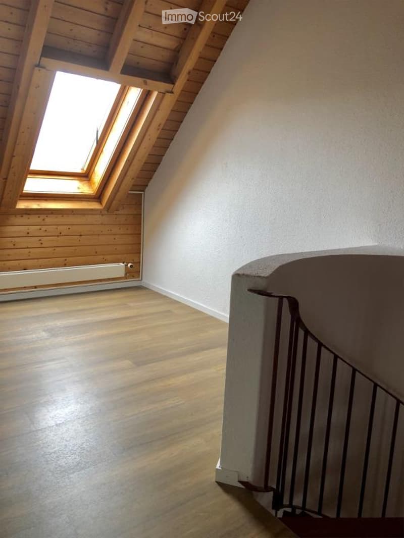 Empty attic room with wooden walls, wooden floor, and skylight window. No furniture or equipment present.