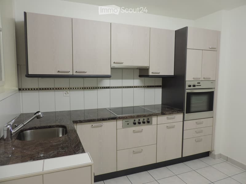 Modern kitchen with light-colored cabinets, stainless steel sink, faucet, and built-in oven. Granite countertop and tiled backsplash.