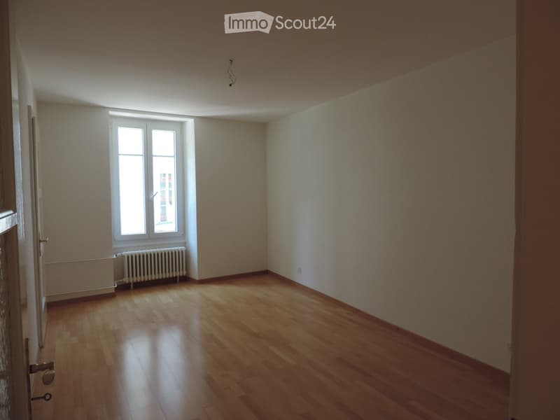 Empty room with wooden flooring, white walls, and a window with a radiator below it. No furniture or equipment is present.