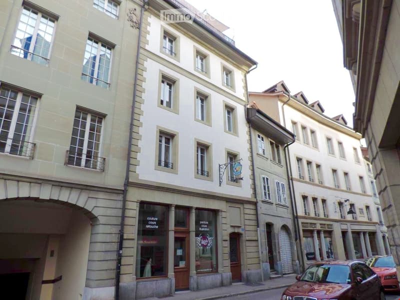 Multi-story building with classic European architecture, large windows, and a storefront at the ground level.
