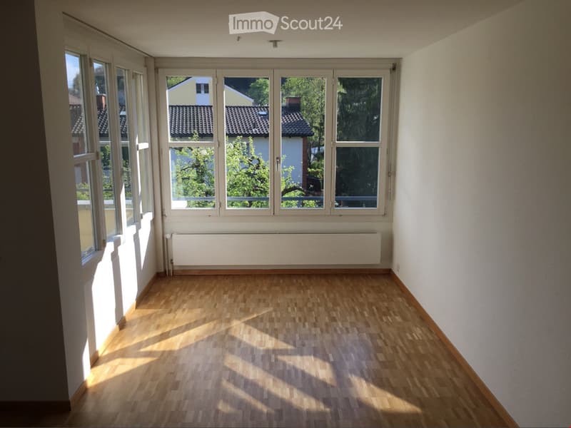 Empty room with wooden flooring, large windows, and white walls. No furniture or equipment present.