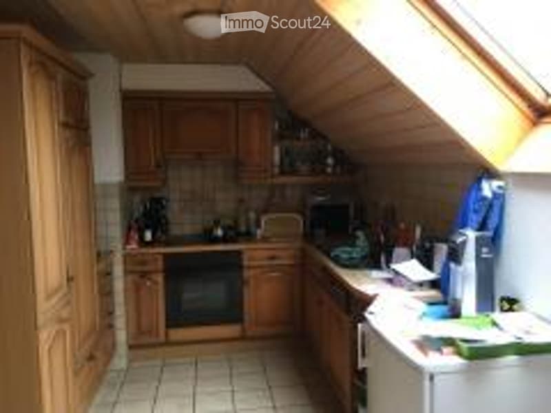 Bright kitchen with wooden cabinets, white tiled floor, and various appliances including a stove, microwave, and refrigerator. Natural light streams in from a skylight above.
