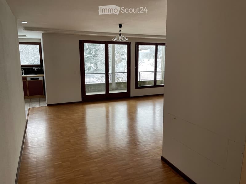 Empty room with wooden flooring, large windows, and a view of a snowy outdoor area. No furniture or equipment is present.