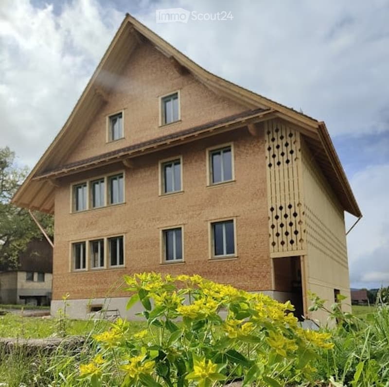 Two-story house with a brown facade, multiple windows, and a decorative wooden lattice on one side.
