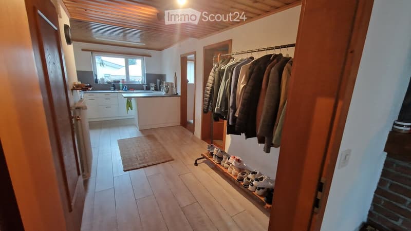 wooden floor, white walls, clothes rack, shoes rack, kitchen with countertop, sink, and window