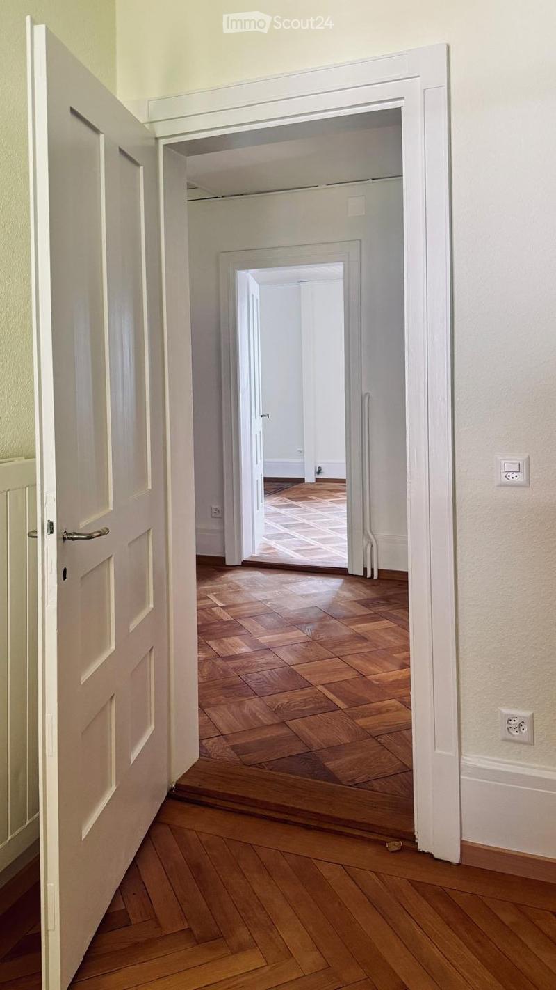 Empty hallway with wooden flooring, white walls, and multiple open doors leading to other rooms.