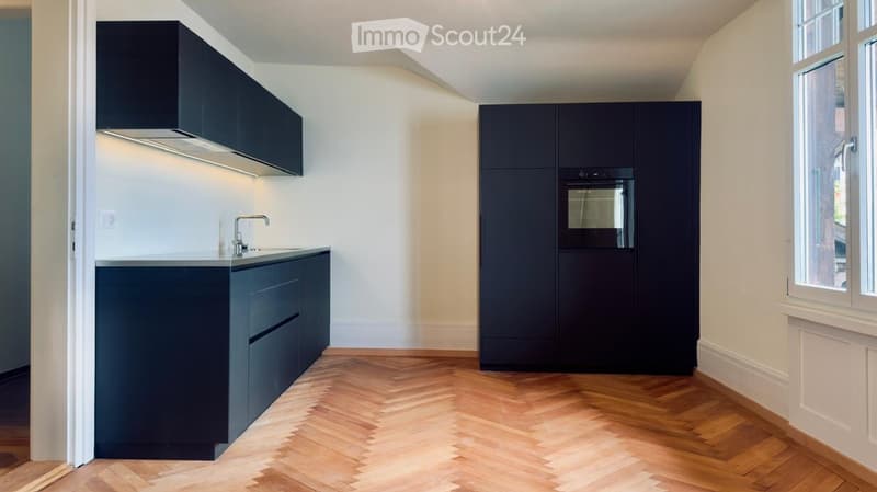Modern kitchen with dark blue cabinets, a white countertop, a sink with a faucet, and an oven. The floor is made of herringbone-patterned wood.