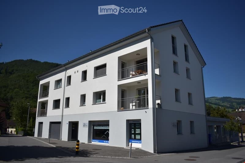 3 story building, white exterior, multiple balconies, garage, windows, door