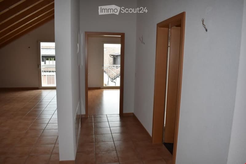Empty hallway with tiled floor, white walls, wooden doors, balcony with railings
