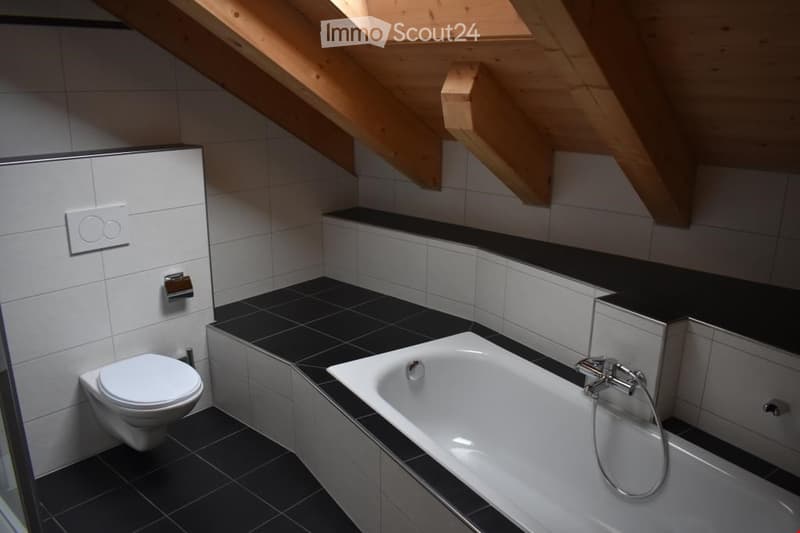 white bathtub, black tiled floor, white tiled walls, wooden ceiling, toilet, shower