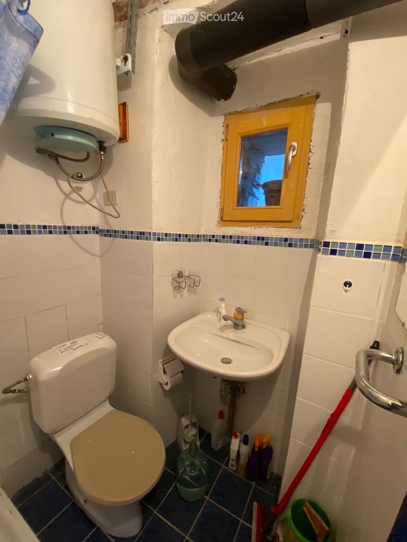 small bathroom with toilet, sink, window, and washing machine