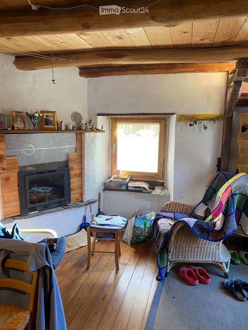 wooden ceiling, fireplace, wooden floor, window, wicker chair, table, books, slippers