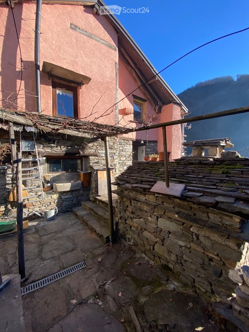 Stone house, raised ground floor, stone wall, ladder, sink, outdoor seating, mountain view