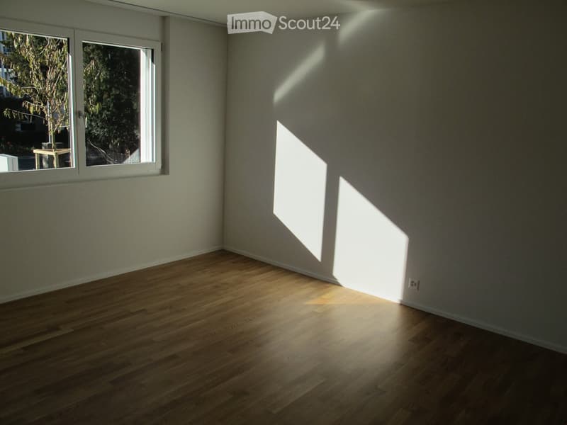 empty room with hardwood floors, white walls, large windows, outlet