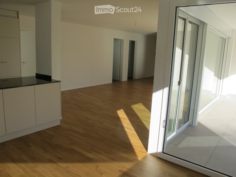 Open floor plan, wooden floor, white walls, sliding glass door, wooden balcony