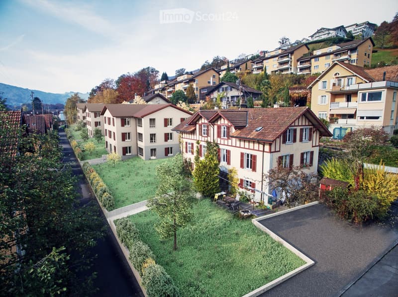 Aerial view of a residential area with multiple houses, green spaces, and a winding road.