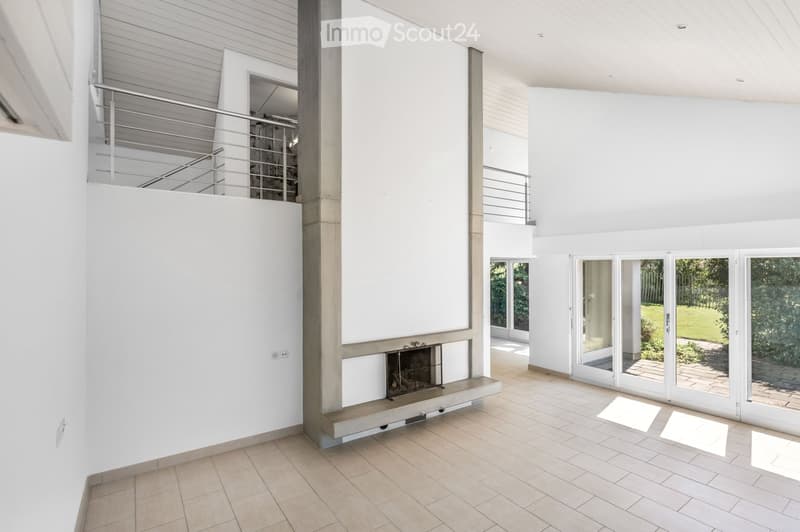 Modern, minimalist living space with white walls, tiled floor, fireplace, large windows, and a staircase leading to an upper level.