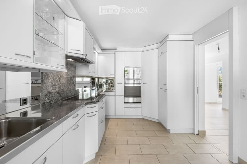 Modern kitchen with white cabinets, stainless steel appliances, granite countertops, and tiled flooring.
