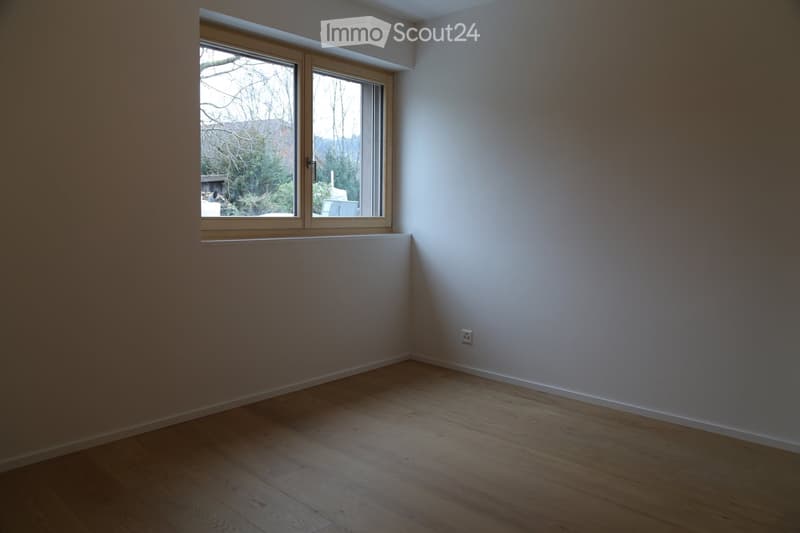 Empty room with wooden flooring, white walls, and a large window with wooden frame. No furniture or equipment present.
