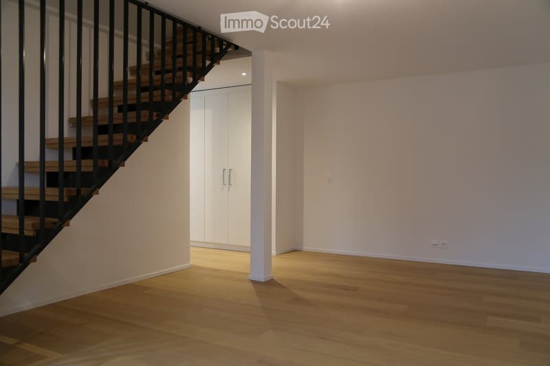 Empty room with wooden flooring, white walls, and a staircase leading upwards. A white closet with double doors is visible in the background.