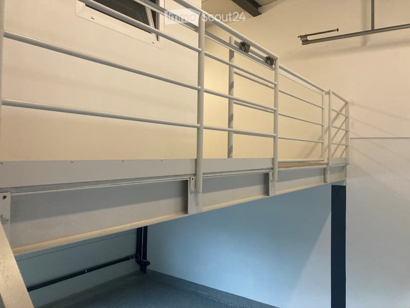 A modern, clean staircase with white railings and blue-painted lower sections, featuring a smooth concrete floor and neutral-colored walls.