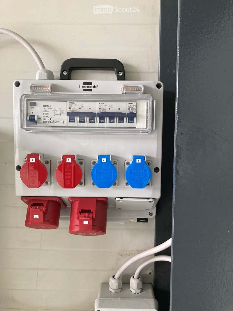 Electrical distribution board with multiple circuit breakers, switches, and power outlets mounted on a wall.