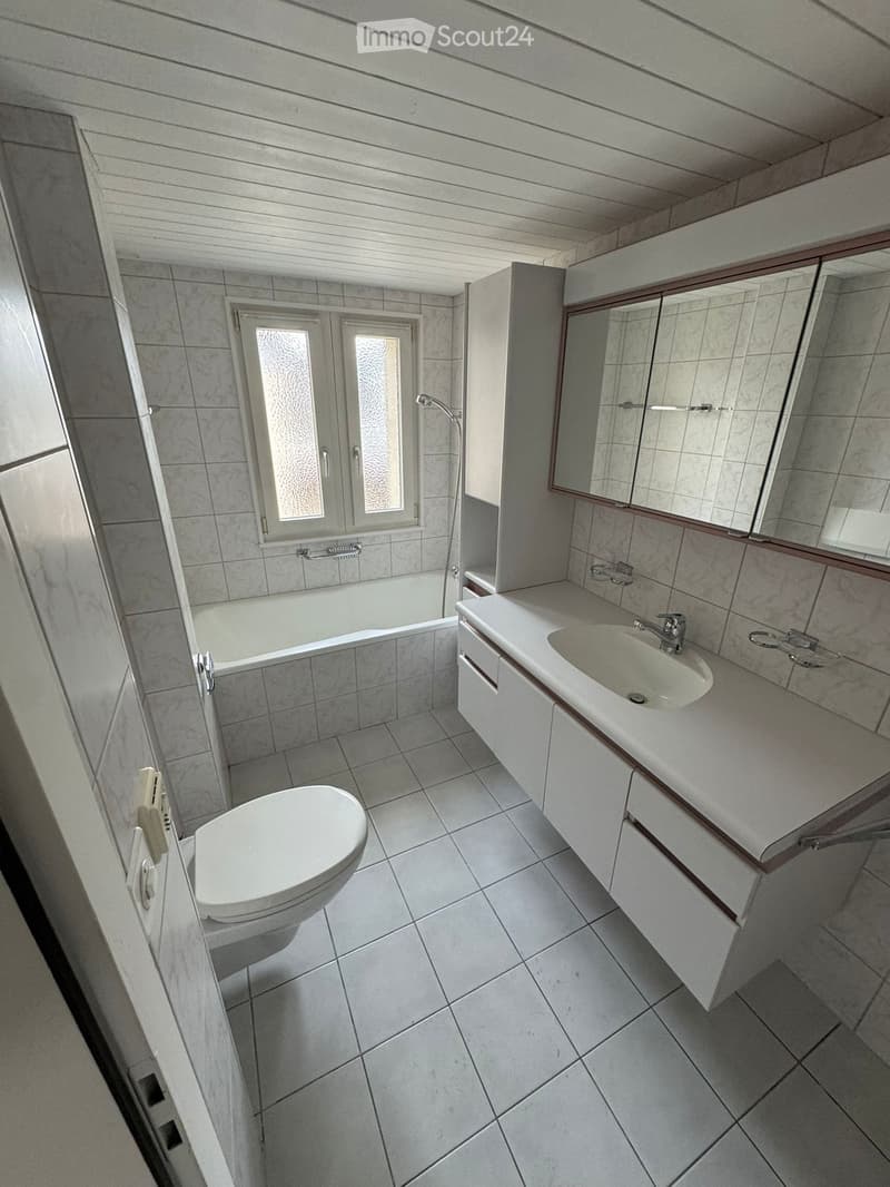 Bathroom with white tiles, bathtub, toilet, sink, mirror and shower area
