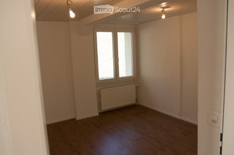 Empty room with wooden flooring, white walls, a single window, and a radiator below it. No furniture or equipment present.