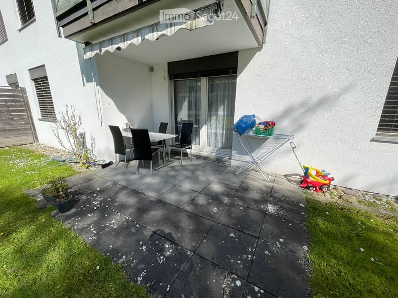 Balcony with a table and chairs, laundry drying rack, and a small toy car nearby.
