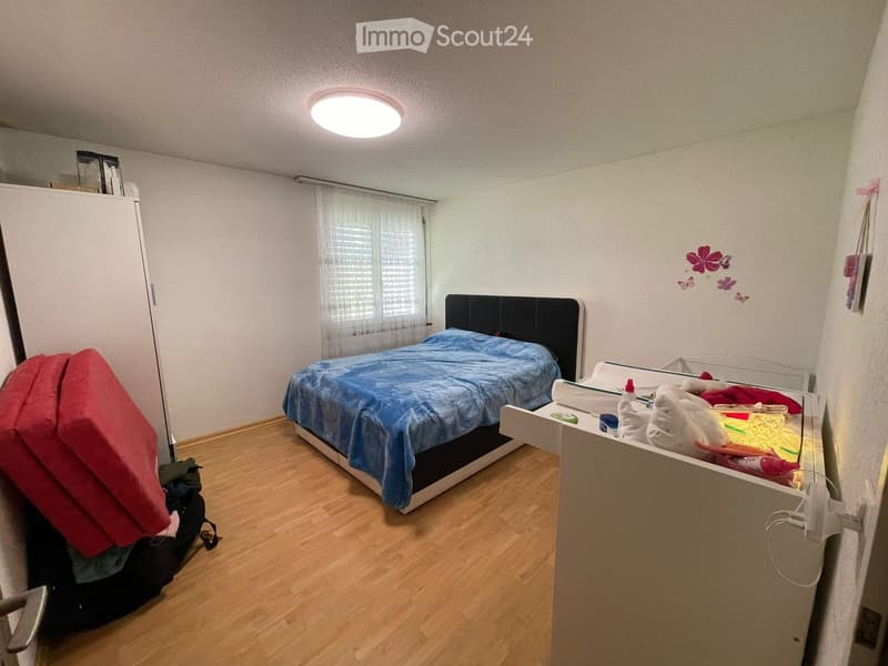 Bedroom with a single bed, blue blanket, wardrobe, and a backpack on the floor.