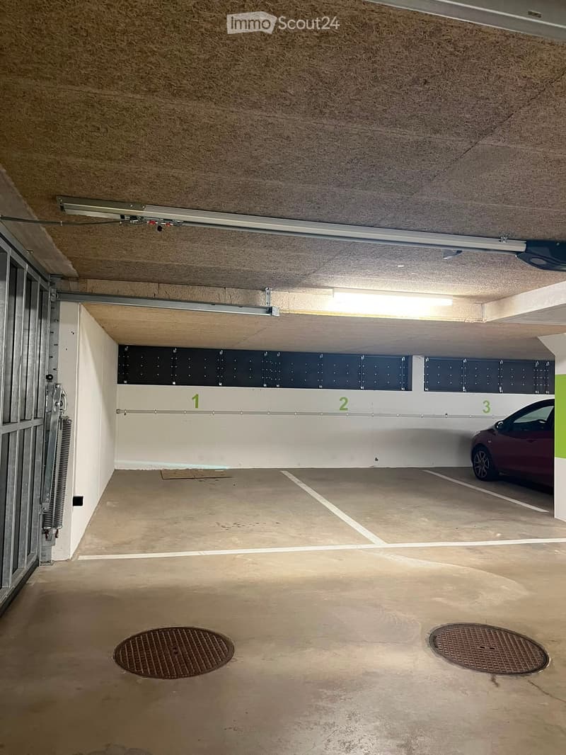 Underground parking area with numbered sections, a parked car, and a raised ceiling with lighting.