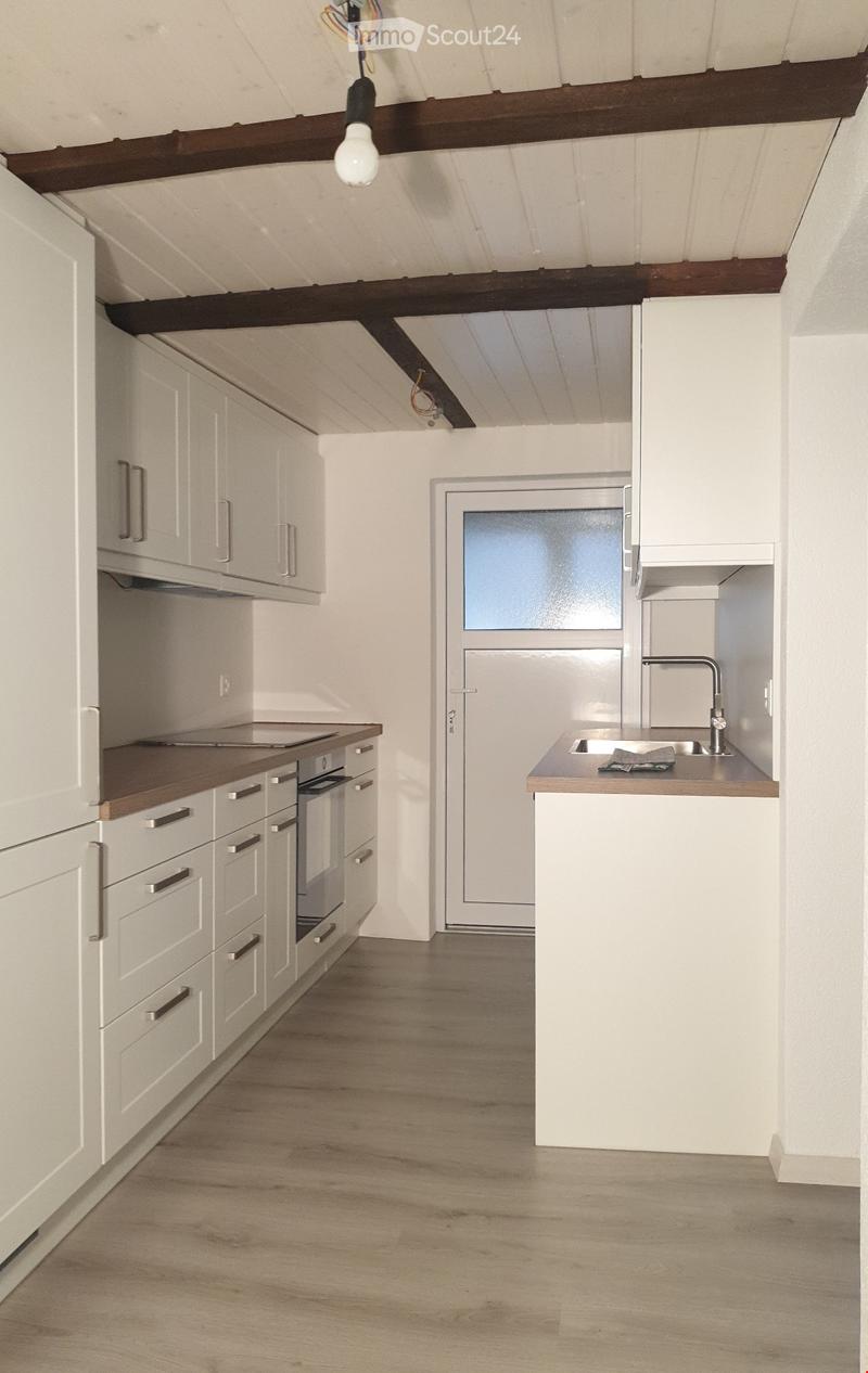 Modern kitchen with white cabinets, wooden countertops, and a central island. Features an oven, sink, and faucet.