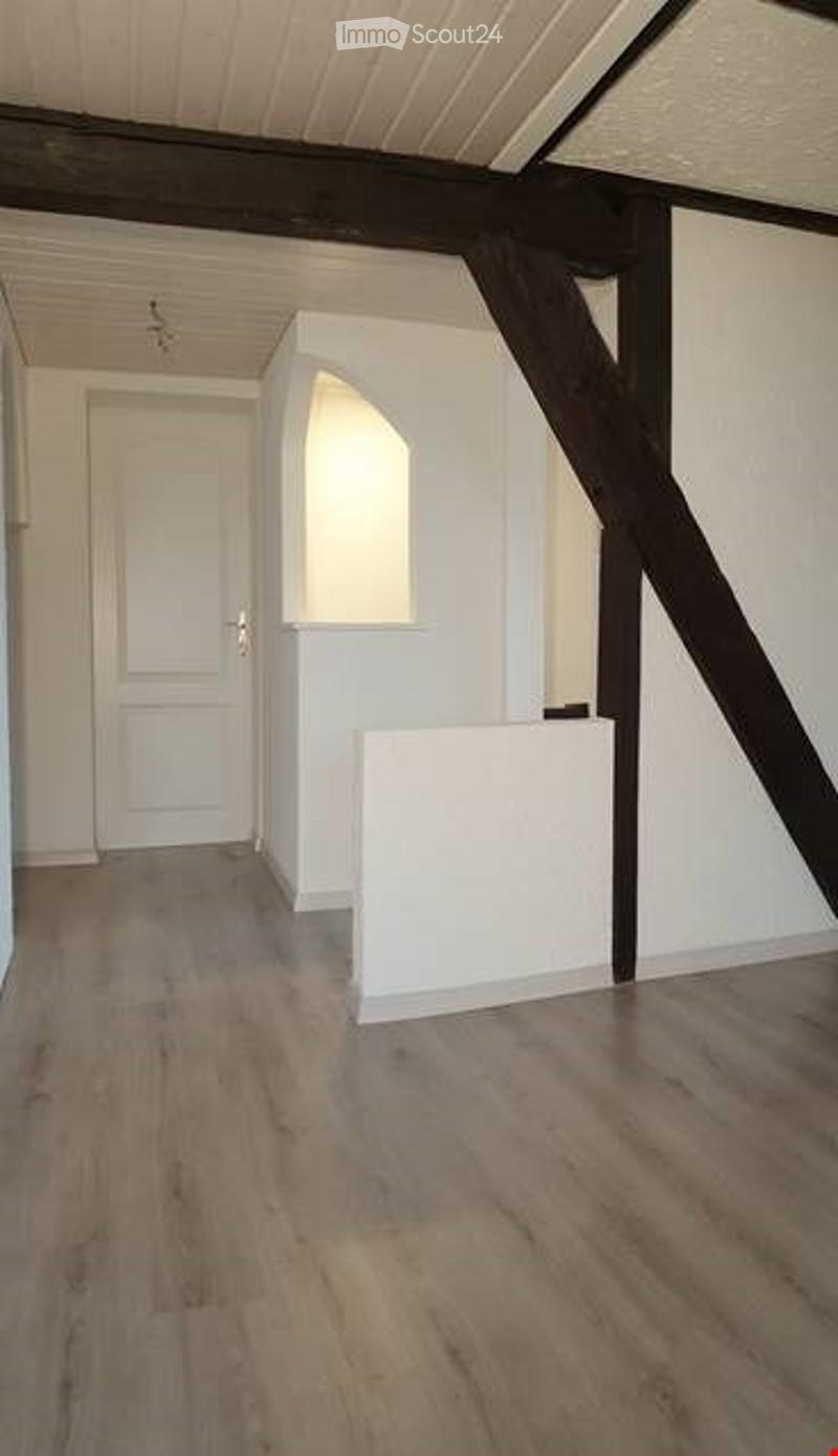 Empty room with wooden flooring, white walls, and a white door. No furniture or equipment present.