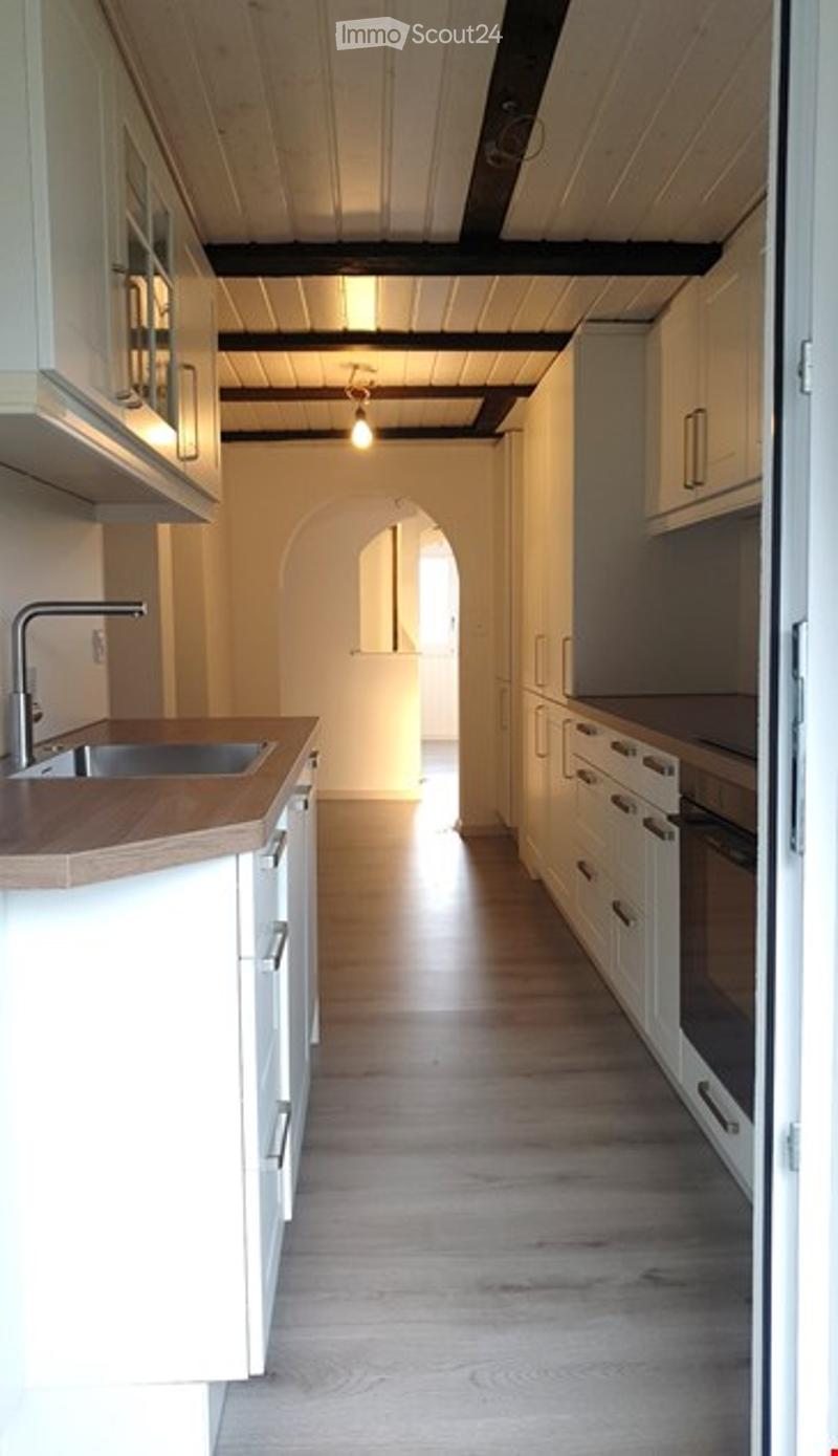 Modern kitchen with white cabinets, wooden countertop, and a sink. The space features a light wooden floor and a warm, inviting atmosphere.