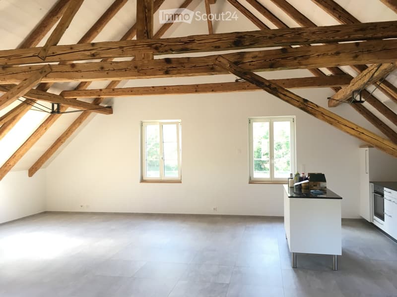 Bright kitchen with exposed wooden beams, white cabinets, and a central island with a black countertop.
